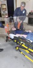 Brian Whitfield, a Woodbury Ambulance Corps junior volunteer, demonstrates how the Lexan box would fit over the head of a patient on an ambulance gurney. The orange tape is only used on the ambulance gurney to keep box immobile during transportation.