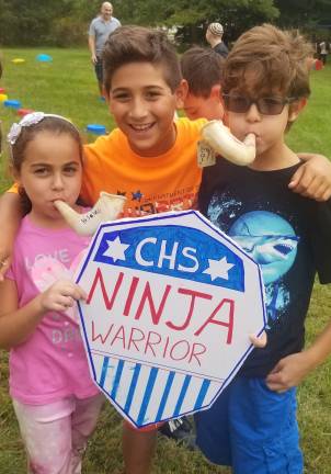 All are welcome at High Holiday Services and children’s programs at Chabad Yasmine Mosker of Monroe (left) and her brother Amir (right), pictured with Ethan Einav of Highland Mills, blow toy shofars at a Chabad Hebrew School High Holiday “Ninja Warrior” competition.