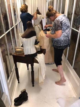 Museum Village staff prepare textile display at the Changing Exhibit Building. The exhibit opens Aug. 31.