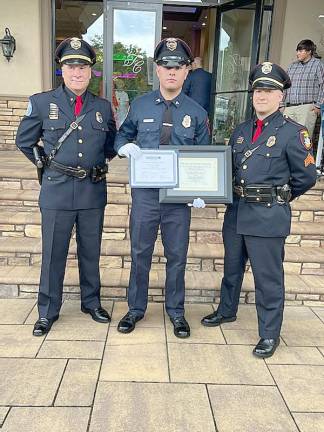 Ptl. Glick, center, is congratulated by Chief James Watt, left, and Sgt. Gregory Kelemen, right.