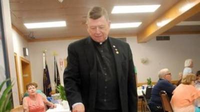 The Rev. Robert Sweeney cuts one his cakes at his retirement party on July 28.