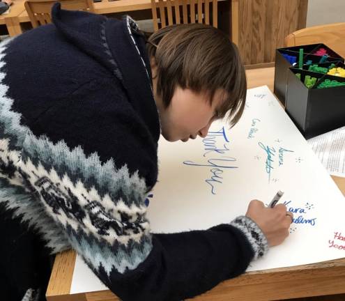 Senior Melissa Moore, a team member for the last four years, takes a break from her astronomy research to sign the thank you card to be given to Lowe’s representatives.