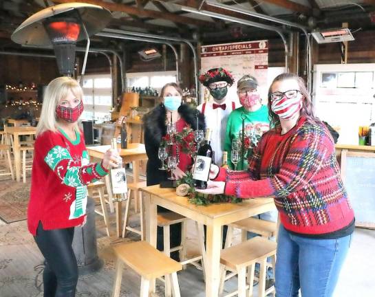 Gathered at the festively dressed pavilion of Applewood Winery to formalize plans for the Dec. 15 Warwick Valley Chamber of Commerce “Virtual Holiday Wine Tasting Mixer” are from left, Warwick Valley Chamber of Commerce Programs Chair Janine Dethmers; Applewood Winery owners Michele, Dylan and Jonathan Hull; and Warwick Chamber Office Manager Bea Arner. Photo by Roger Gavan.