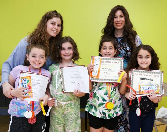 School director Chana Burston and teacher Lulu Feldman present awards of achievement to nine-year-old students Alana Schrank of Goshen, Fiana Goldenberg of Warwick, Bella Redling of Warwick. and Yasmine Mosker of Monroe