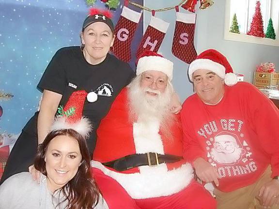 Susan and Rick Bossley pose with Santa on “Pet Photos with Santa Day at the Goshen Humane Society. With them is shelter volunteer Corinne Wood, owner of two rescue pit bulls.