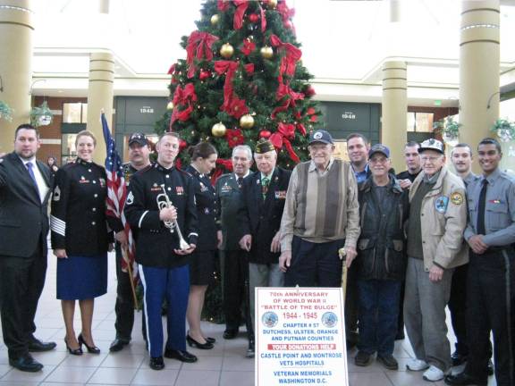 70 years ago, in a dark and snowy wood Battle of the Bulge 70th anniversary commemoration at the Galleria. From left: Starting from left, Dan Depew, Wallkill Town Supervisor; Major Shauna Hann, West Point; a member of Rolling Thunder Vietnam Veterans group; Staff Sgt. Jeffrey Wissner, bugler from West Point; M/Sgt. Mary Kaye Messenger, soloist from West Point; Brig. Gen. NYG (Ret.) Eliot Herman; NYS Senator Bill Larkin; Veteran Ralph Ousterhoudt; County Executive Steve Neuhaus; Veteran Vincent Marino; Deputy Vincent Iannuzzi of the Orange County Sheriff's Department; Veteran and former P.O.W. Harvey Horn; and Corporal Spencer Sutherland and Staff Sergeant Nigel Balgobin from the Orange County Sheriff's Office (Photo by Ginny Privitar)