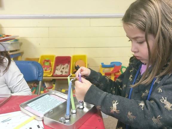 Abby playing set up with her new travel menorah.