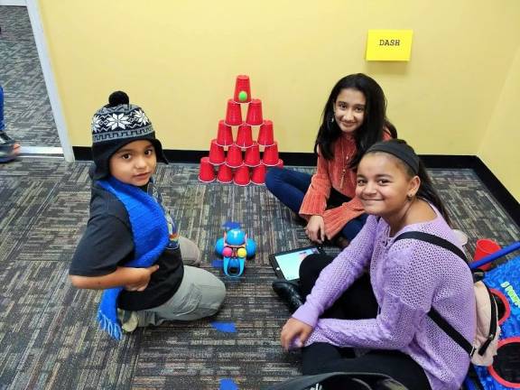 Tanya Sinha, center, with friends. The robot has just released the green ball hitting the pyramid (Photo by Ginny Privitar)