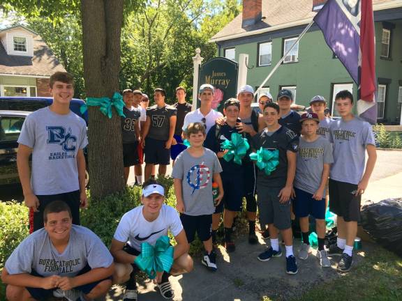 The Burke football team tie blue ribbons for ovarian awareness throughout the Village of Goshen (Photo provided)