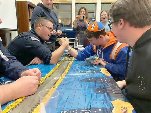 Jared Pincus, of Florida, NY, competes in an arm wrestle with Officer Payton of the Village of Monroe Police Department at CTeen’s “Chocolates for Cops” at the Chabad Center in Chester