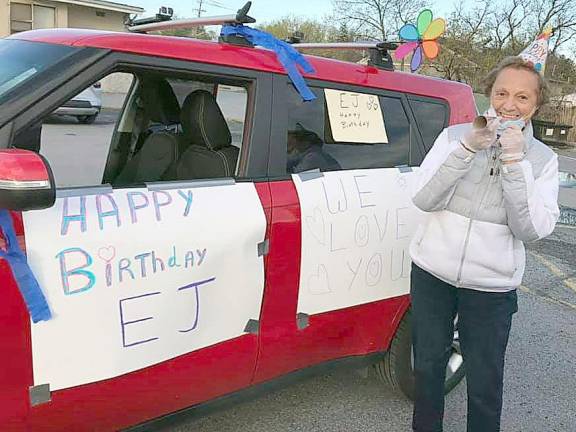 One of a line of 32 cars that paraded in front of E. J. Szulwach's house in celebration of his birthday on March 28. Marian Zangrillo lowers her mask for the picture.