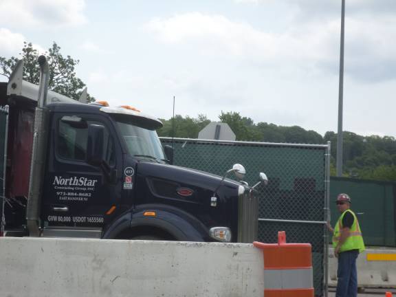 A truck carrying debris from the Orange County Government Center demolition is led out of the gate of the parking lot by a worker from Holt Construction, which is overseeing the estimated $77 million renovation project. (Photo by Nathan Mayberg)