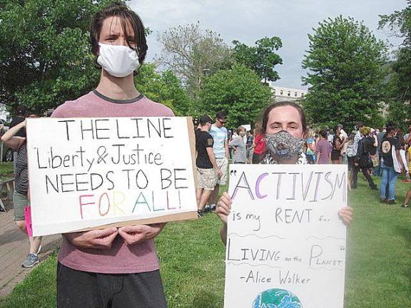 Nicholas Moore and Briana Spina, from Albany, hold up their signs of support for the movement. Moore's said, “Liberty and Justice needs to be for all.” Spina’s sign read: “Activism is my rent for living on this planet,” a quote from Alice Walker, activist and author of the novel, “The Color Purple.” Photo by Geri Corey.