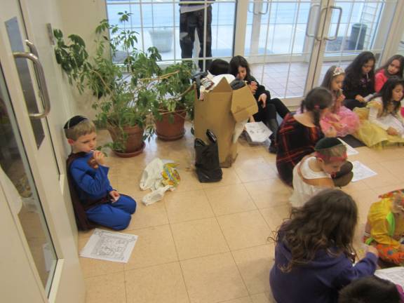 Flower children gather to celebrate Purim David Forman of Goshen listens to the Meghila reading with the other children.