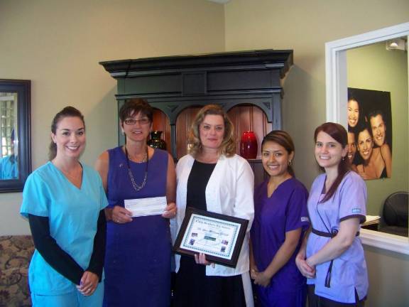 Reason to smile: A big donation for Big Brothers Big Sisters Lane McEwan, DDS (center), and her staff present Big Brothers Big Sisters of Orange County Executive Director Nancy Kosloski (second from left) with a check for $1,380, the local contribution from McEwan’s Smiles For Life Campaign run this past summer. From left: Krissy Karras, Kosloski, Dr. McEwan, Marilyn Valencia, and Denise Gualtieri.