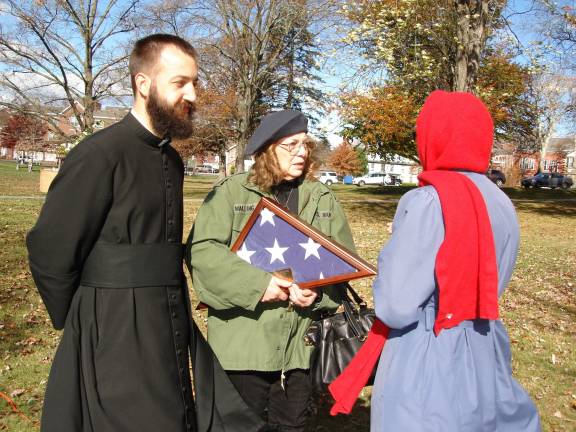 A stirring ceremony at Goshen memorial Eileen M. Morey of Goshen holds a folded, boxed flag presented to her in honor of William L. Walling, past commander for the VFW in Middletown who died on May 8, 2016. Walling lived in Goshen. With Morey is Father Jeff Pomeisl, Parochial Vicar at St. John the Evangelist Church and Grace Roeder of Campbell Hall (Photo by Geri Corey)