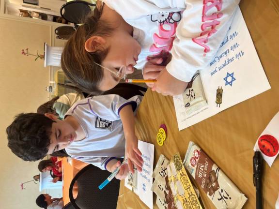 Seventh-grade students from Goshen write letters packaged with sweets to soldiers in the Israel Defense Forces at Chabad Hebrew School with Rabbi Pesach and Chana Burston.