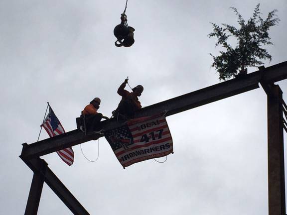 'Topping out' ceremony held at government center Two Local 417 Ironworkers hoist the beam into place on top of Division 2 (Photo provided)
