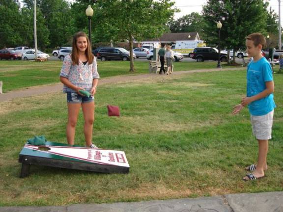 Village Park game Cornhole created by Goshen Girl Scout Jason Barnes demonstrates how to play Cornhole as his sister Alex watches. She constructed and erected the game in Village Park for all residents to play.