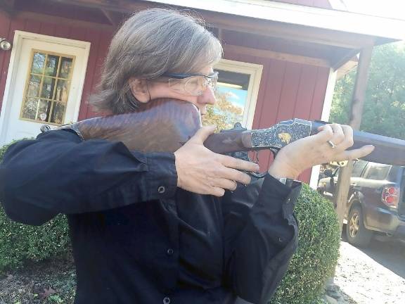 Shuttleworth holding finished gun in shooting position. Notice the three parts – lock (in the middle) the firing mechanism, stock (polished and crafted to fit on her shoulder for balance), and barrel (skinny round part where the bullet travels through). Hence the expression lock, stock and barrel means everything.”