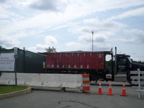 A truck carrying debris from the Orange County Government Center demolition is led out of the gate of the parking lot by a worker from Holt Construction, which is overseeing the estimated $77 million renovation project. (Photo by Nathan Mayberg)