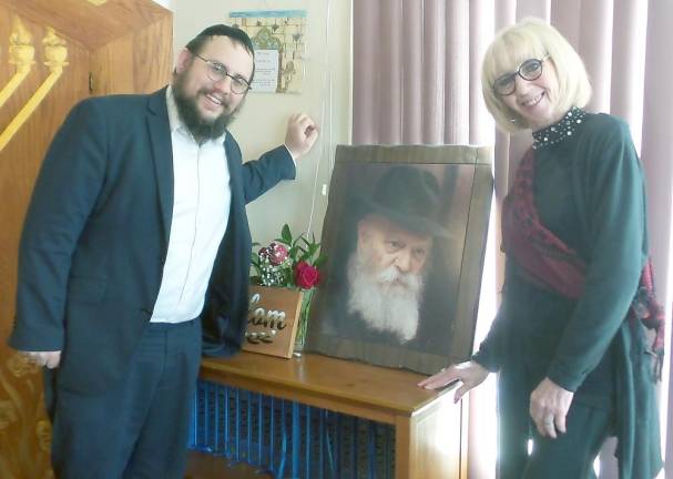 Rabbi Meir Borenstein and Diane Greenwald with a portrait of Rabbi Schneerson, The Lubavitcher Rebbe, who founded the Chabad movement.