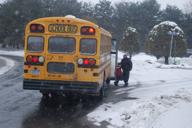 Photo by Nathan Mayberg A man helps a boy off the bus in Chester following an early dismissal during the snow on Monday afternoon.