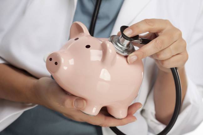 Female Doctor Holding Stethoscope to Pink Piggy Bank Abstract.