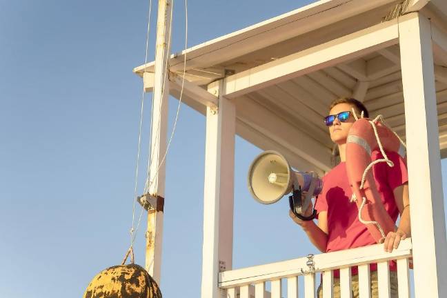 The lifeguard is watching the beach from the surveillance tower