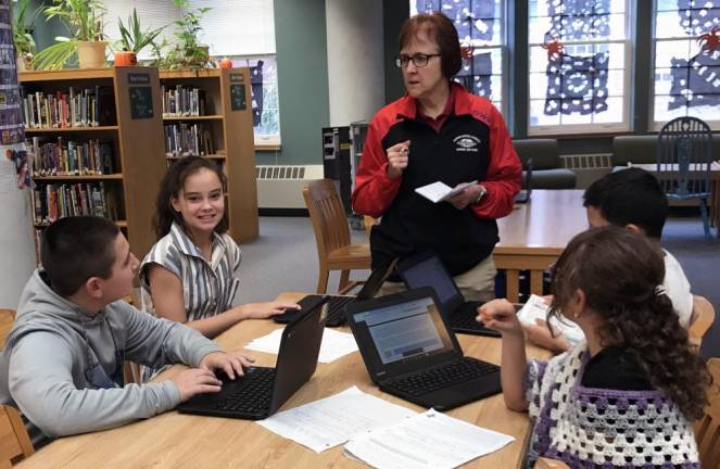Head coach Becky Dendanto gives pointers to members of the Science Olympiad team in one of their library sessions.