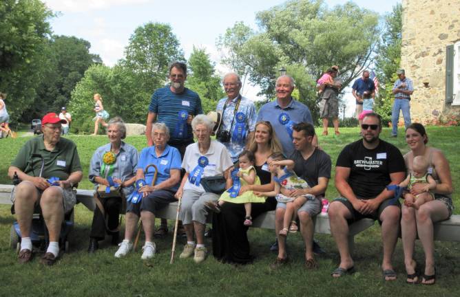 A great day for the Bull family The blue ribbon winners: right, Jim Mitchell-whose birthday it was, along with Shirley Matthews.Seated: Bob Otto, oldest man; Shirley Matthews, celebrating a birthday; Paula Otto, Bob’s wife of 67 years; Harriet Clark, oldest woman, Caroline Goslee, youngest girl; her mother, Rebecca, sister Elizabeth and dad James Goslee; Curtis Johnson, dad, and mom Heather of baby Evan Johnson, the youngest boy. (Photo by Ginny Privitar)