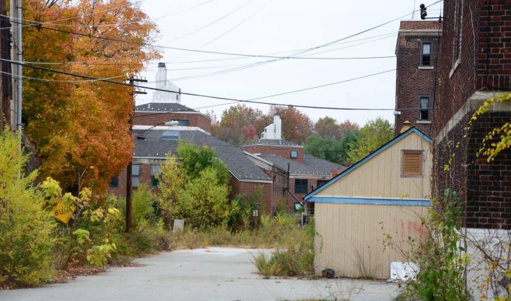 Camp LaGuardia at the crossroads A maintenance shed at right and twin barracks crowned by smokestacks at center along a pitted road behind Camp LaGuardia's Main Building. Courtesy of Robert Yasinsac / Hudson Valley Ruins.