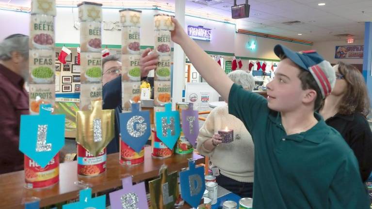 Max Hershkowitz of Highland Mills lights a “Can-orah” candle at Colonial Lanes in Chester.