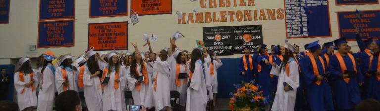 Chester graduates throw their caps in the air in celebration.