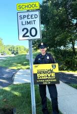 Goshen High School Resource Officer Darren Swensen holds a sign urging safe dri