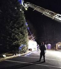 Firefighters of Walton Engine and Hose braved the bitter cold and wind Monday night to use their ladder truck to put up the strings of lights on the large outdoor tree at the Erie Station in Chester in preparation for the community tree lighting on Sunday, Dec. 5. Photo by Lynn Berenberg.