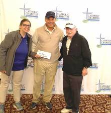 Catholic Charities CEO Shannon Kelly, left, presents a prize to the first-place men’s foursome from Chartwell Strategy Group: Dave Tamasi (center) and Richard Cignarella (right) accept on behalf of their team.