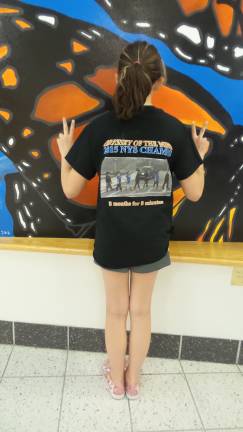 Team member Carolyn Harvey shows the back of their T-shirt, which pithily describes what Odyssey is all about: "8 months for 8 minutes" (Photo by Frances Ruth Harris)