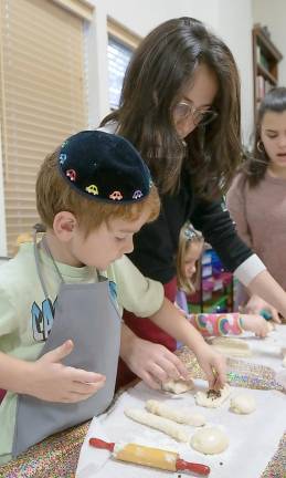 Yitty Farkas, 13, of Monroe helps Hanok Larson, 5, of Monroe, to braid his challahs at Chabad of Orange County’s Loaves of Love event. One challah will be given to a friend, and one will be shared with family.