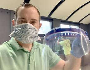 Goshen High School Assistant Principal Kyle Roddey holds one of the protective masks that he and technology teacher Joe Fedor are manufacturing in the high school STEAM Lab. The masks will be donated to local medical personnel.