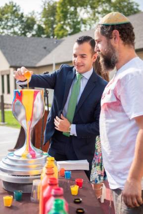Chabad alum Lee Stanton, formerly of Greenwood Lake, now a NYPD officer in NYC, pours his blessing onto the “Cup of Overflowing Blessings” pop-art sculpture at the Grand Opening Celebration of the new Chabad Center for Jewish Life.