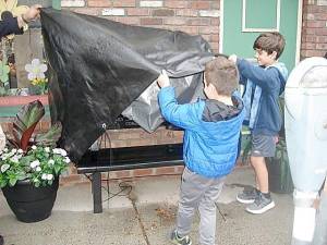 Mike Nuzzolese’s grandsons, James and Daniel, unveil the granite bench, located in front of Joe’s Fix Its on