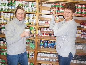 Heather Larsen, left, gives Betty Smith help in stocking the shelves at the Goshen Food Pantry, located in the loft of the First Presbyterian Church in the Village of Goshen. Larsen has been helping out in stocking shelves and bagging for three years. Photo by Geri Corey.