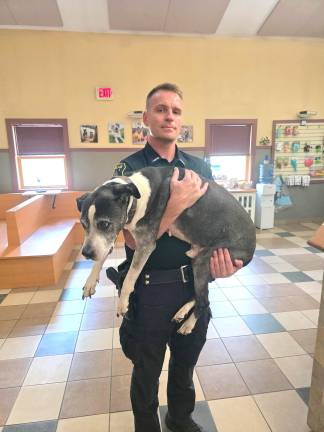 Town of Goshen Police Officer Terrence Moore helps an elderly resident get his sick dog to the veterinarian for treatment.