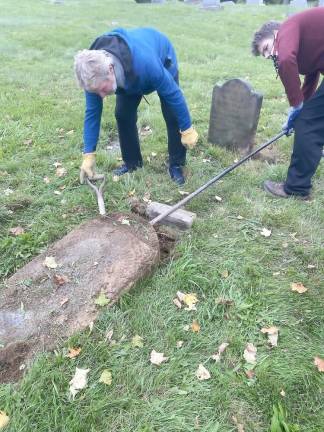 Raymond Quattrini and Sam Lieneck in Slate Hill Cemetery using a lever to lift one of the gravestones from the mid-1800’s which had been disappearing below ground.