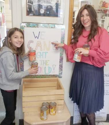 Chana Burston, along with Chabad Hebrew School student Lizzie Deskin of Monroe place canned food in the donation baskets at Chabad. The canned goods will be used Dec. 2 to form a Can-orah, which will then be donated to local food pantries.