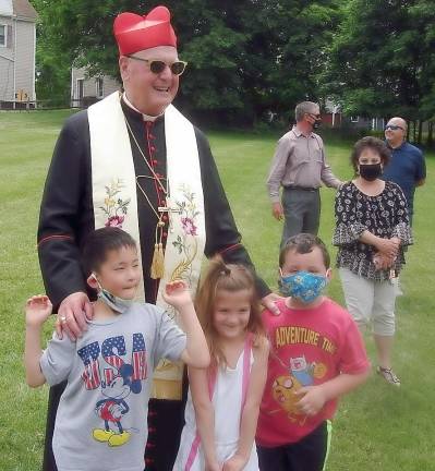 Cardinal Dolan with three children who enjoy the playground at the Faith First @ St. Columba preschool: from left to right: Logan Stamp, 9, Mia Faist, 5, and Devin Stamp, 5. Photos by Geri Corey