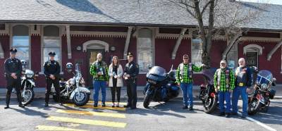 Village of Goshen Mayor Molly O’Donnell (center) stands next to Nam Knight President John “Cheech” Richichi (left) and Village of Goshen Police Chief Ryan Rich (right), along with members of the police department’s motorcycle unit and members of the motorcycle club.