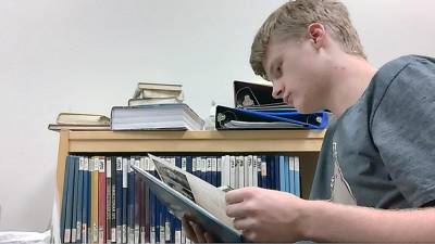 Caleb Garver, grade 11, looks through some old yearbooks as part of his work on “The Maple Avenue Memorial Film