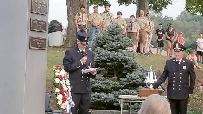 Firefighter Ed Stoddard, organizer of the memorial event, reads the names of the Chester community residents lost on September 11, 2001. He is pictured at the 9/11 memorial with firefighter Joe McCourt and members of the local Boy Scout Troop.